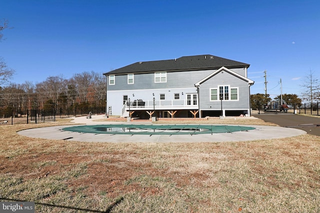 back of house featuring a fenced in pool, fence, a wooden deck, a patio area, and a lawn