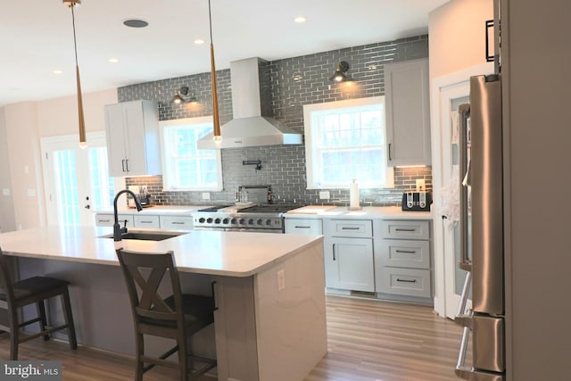 kitchen featuring a sink, decorative backsplash, stove, and wall chimney exhaust hood