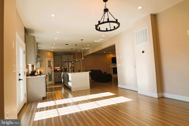 interior space with wood finished floors, baseboards, visible vents, recessed lighting, and a chandelier