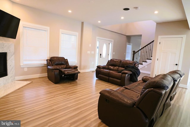 living room featuring stairway, recessed lighting, a fireplace, and light wood finished floors