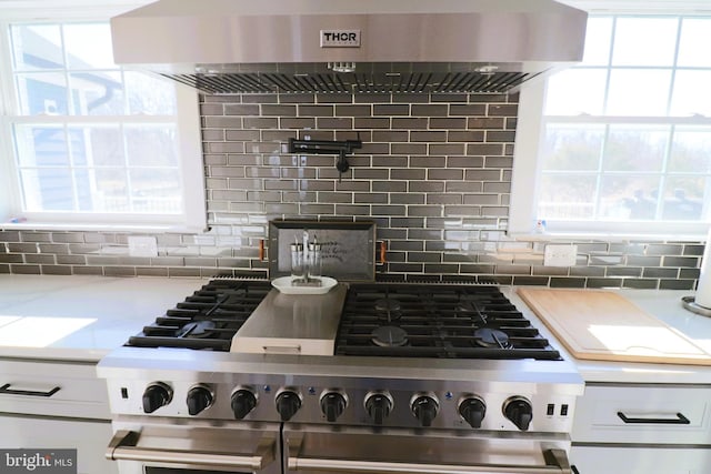 kitchen with decorative backsplash, wall chimney range hood, and a wealth of natural light