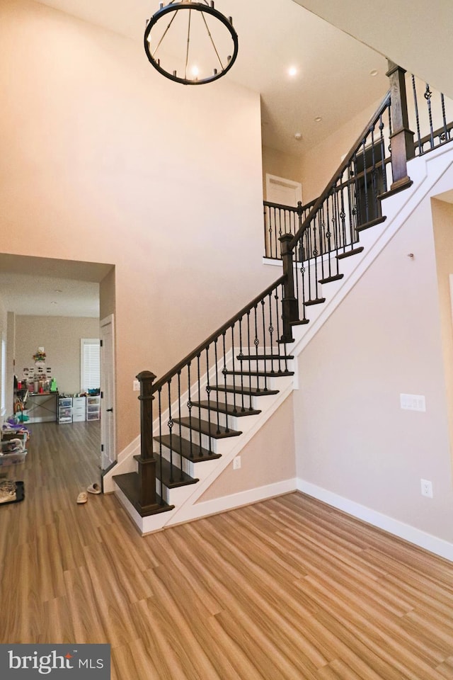 stairs with recessed lighting, baseboards, a high ceiling, and wood finished floors