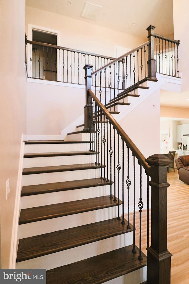 staircase featuring a high ceiling and wood finished floors