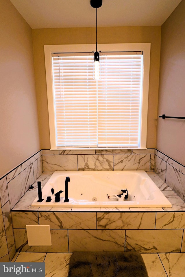 bathroom with marble finish floor and a jetted tub