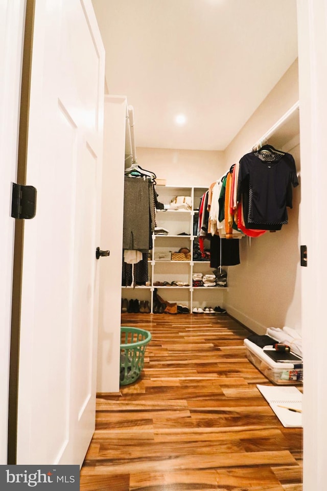 walk in closet with wood finished floors