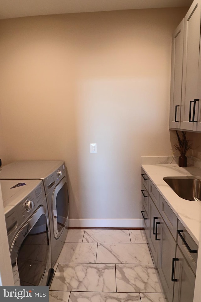 laundry area featuring independent washer and dryer, marble finish floor, a sink, cabinet space, and baseboards