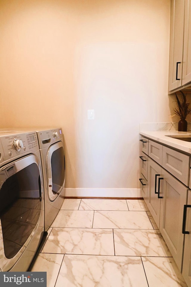 laundry room with marble finish floor, a sink, washing machine and dryer, cabinet space, and baseboards