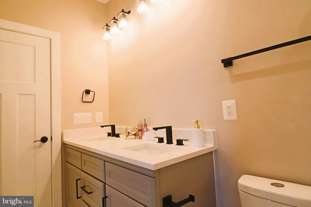 bathroom featuring a sink, toilet, and double vanity