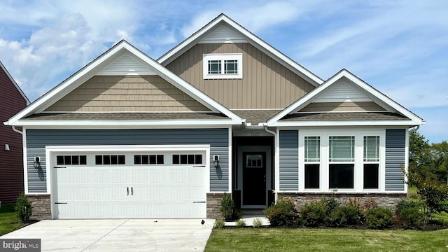 craftsman house featuring stone siding, an attached garage, concrete driveway, and roof with shingles