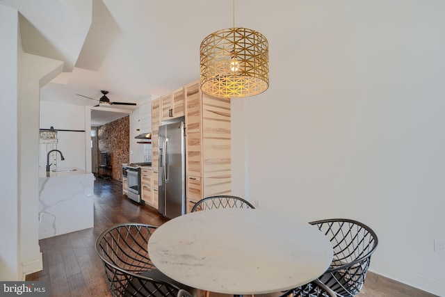 dining space featuring ceiling fan with notable chandelier, baseboards, and dark wood-style flooring