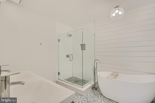 bathroom featuring a sink, a freestanding tub, a shower stall, and tile patterned flooring