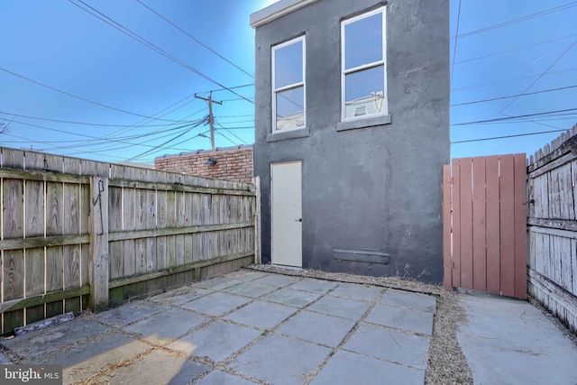 rear view of property with a patio, fence, and stucco siding