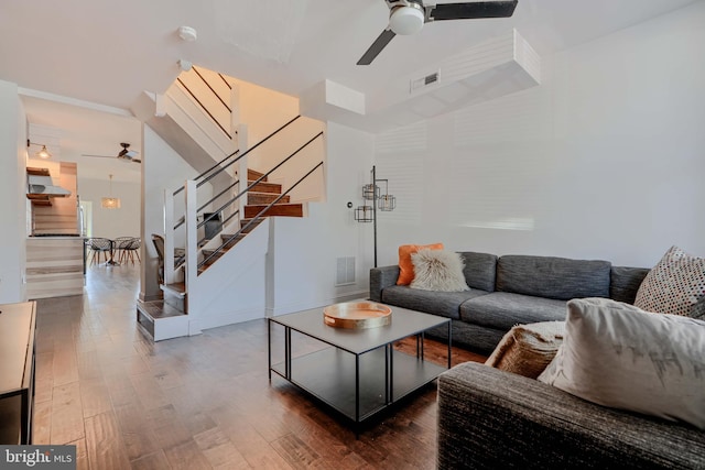 living area with ceiling fan, visible vents, wood finished floors, and stairs