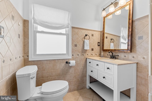 bathroom featuring tile patterned flooring, toilet, vanity, and tile walls