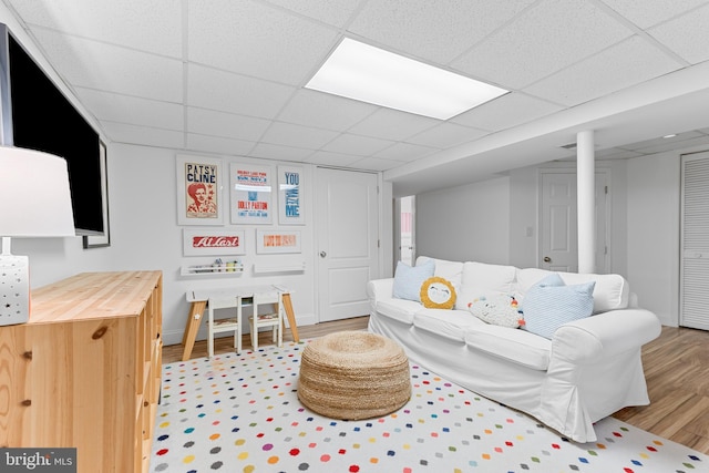 living room with a paneled ceiling, baseboards, and light wood finished floors