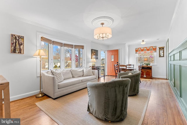 living area with wood finished floors, baseboards, and ornamental molding