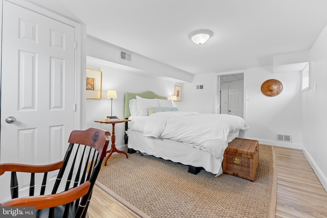 bedroom with visible vents, baseboards, and wood finished floors