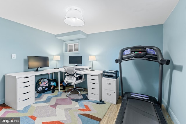 home office with light wood-style flooring and baseboards