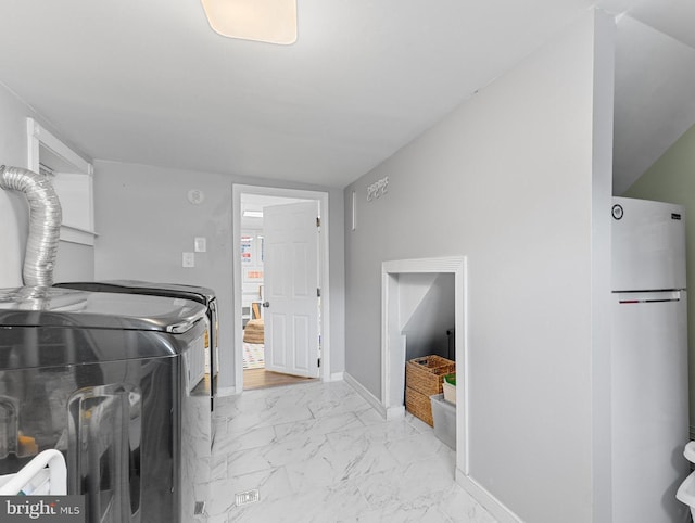 clothes washing area with washing machine and dryer, laundry area, marble finish floor, and baseboards