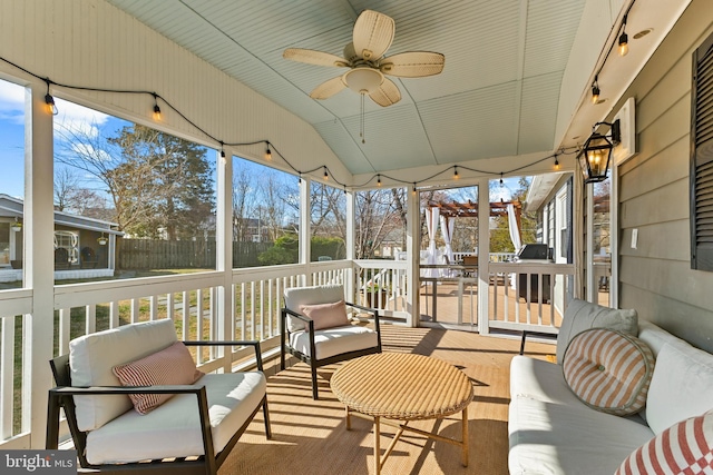 sunroom / solarium with lofted ceiling, a healthy amount of sunlight, track lighting, and ceiling fan