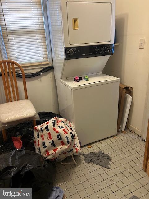 laundry room with light tile patterned floors, laundry area, and stacked washer / dryer