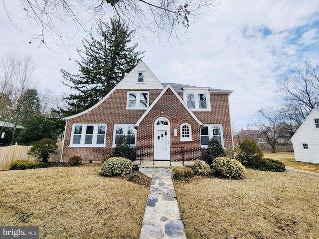 view of front of property with brick siding, a front yard, and fence