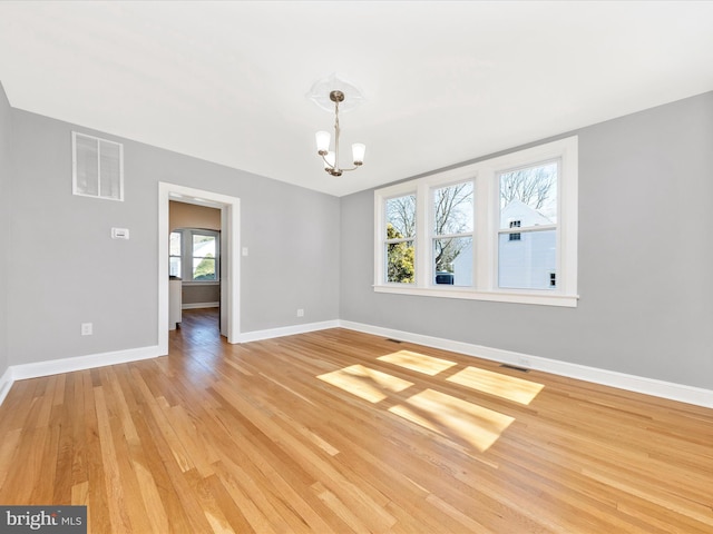 unfurnished room with visible vents, baseboards, an inviting chandelier, and light wood-style flooring