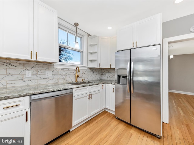 kitchen with a sink, decorative backsplash, white cabinets, and stainless steel appliances