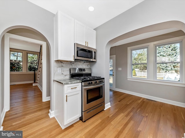 kitchen with tasteful backsplash, plenty of natural light, white cabinets, and stainless steel appliances