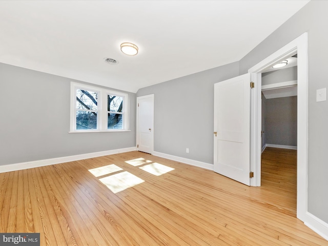 unfurnished bedroom with visible vents, light wood-style flooring, and baseboards