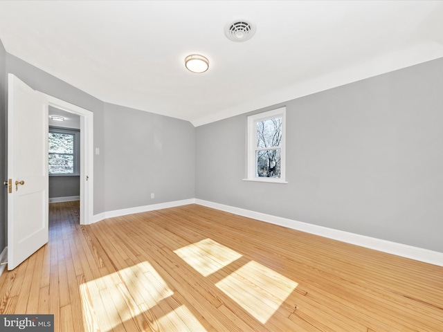 spare room with vaulted ceiling, baseboards, visible vents, and light wood-type flooring