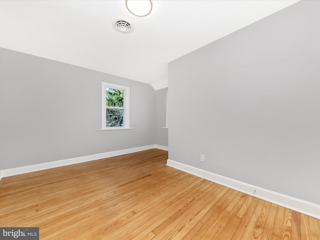 unfurnished room featuring lofted ceiling, wood finished floors, visible vents, and baseboards