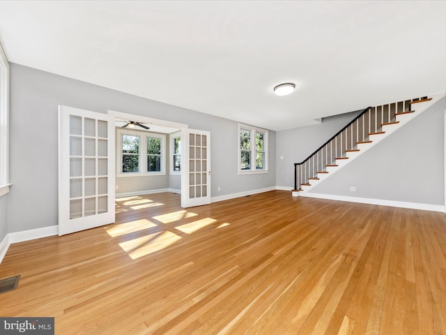 unfurnished living room with stairway, baseboards, visible vents, and light wood finished floors