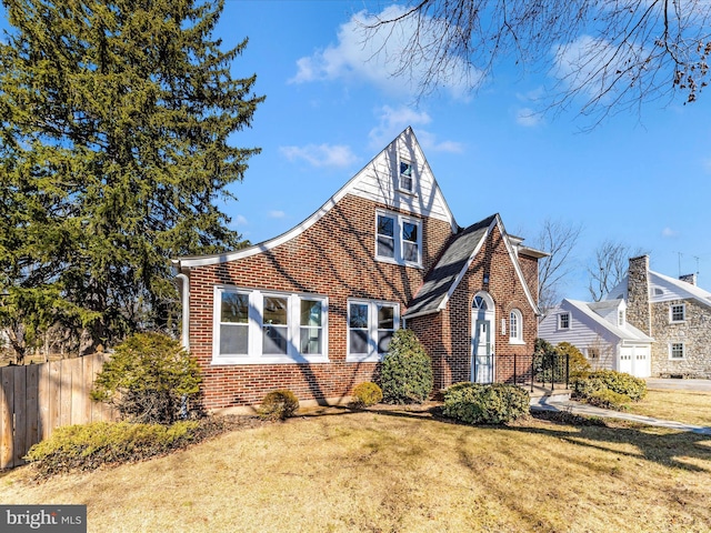 view of front of house featuring brick siding, a front lawn, and fence