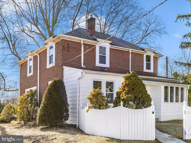 view of home's exterior featuring fence, brick siding, and a chimney