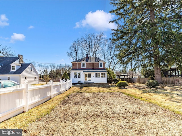 back of property with a chimney and fence