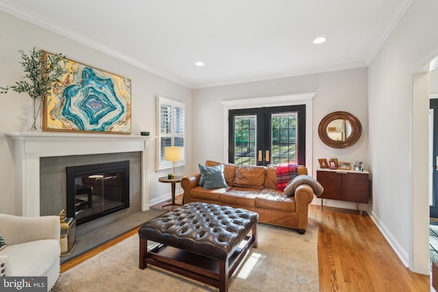 living room with crown molding, baseboards, french doors, wood finished floors, and a glass covered fireplace