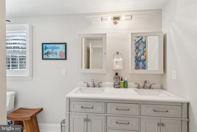 full bath with a sink, baseboards, toilet, and double vanity