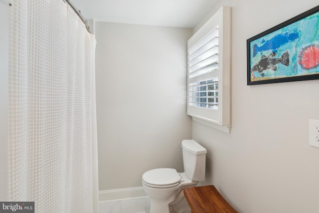 full bath with curtained shower, toilet, and baseboards