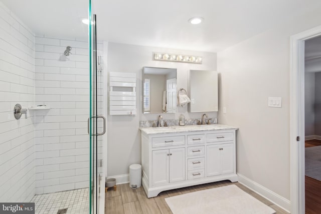 full bathroom with a stall shower, wood finished floors, baseboards, and a sink