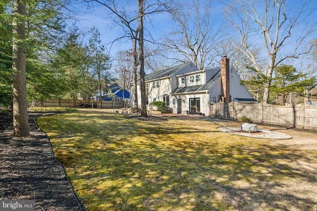 back of property featuring a yard, french doors, a chimney, and fence