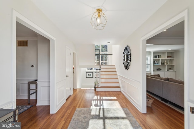 foyer featuring visible vents, wood finished floors, stairs, and a decorative wall