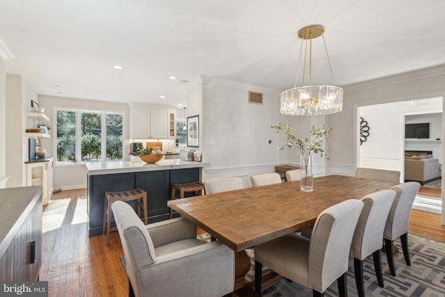 dining area with light wood finished floors, visible vents, ornamental molding, recessed lighting, and a notable chandelier