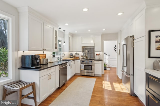 kitchen with white cabinets, light wood-type flooring, high end appliances, and a sink