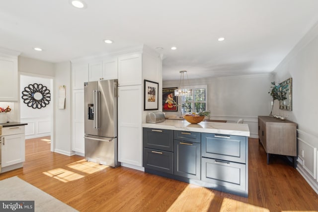 kitchen featuring light wood finished floors, white cabinetry, crown molding, a decorative wall, and high quality fridge