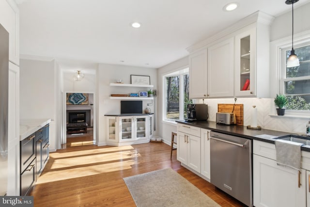 kitchen featuring light wood-style floors, stainless steel dishwasher, pendant lighting, and white cabinets