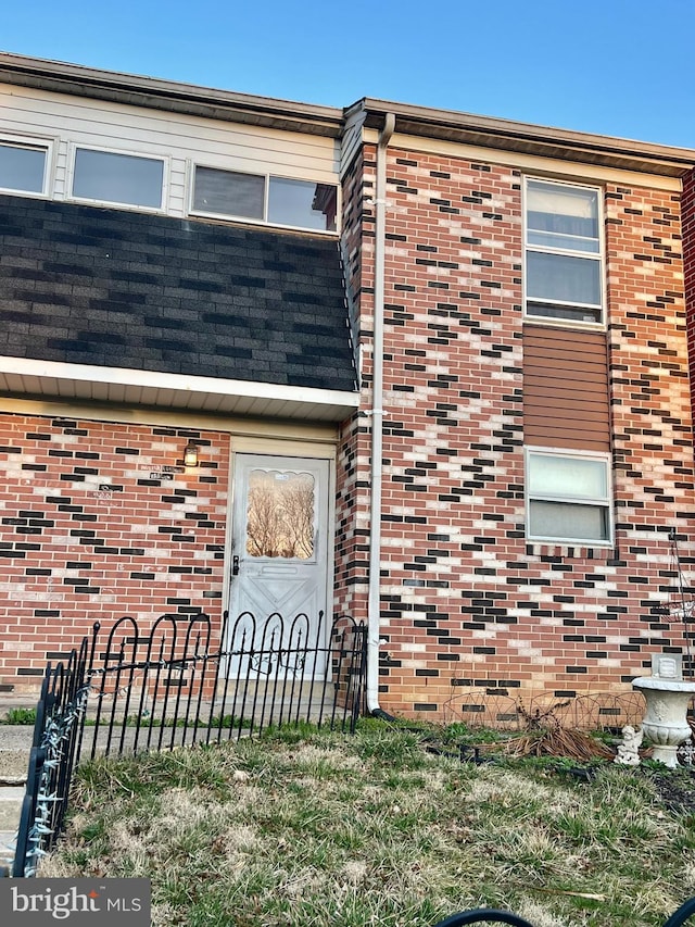 entrance to property featuring fence and brick siding