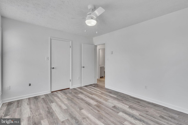 unfurnished bedroom featuring ceiling fan, a textured ceiling, baseboards, and wood finished floors