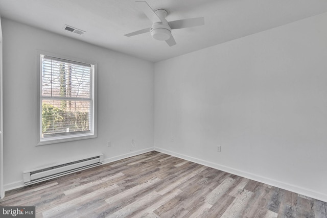 unfurnished room with visible vents, a baseboard heating unit, baseboards, wood finished floors, and a ceiling fan