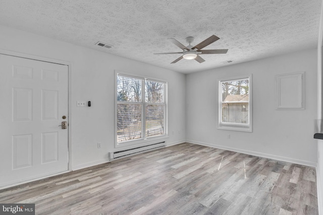 foyer with a baseboard heating unit, wood finished floors, visible vents, and baseboards